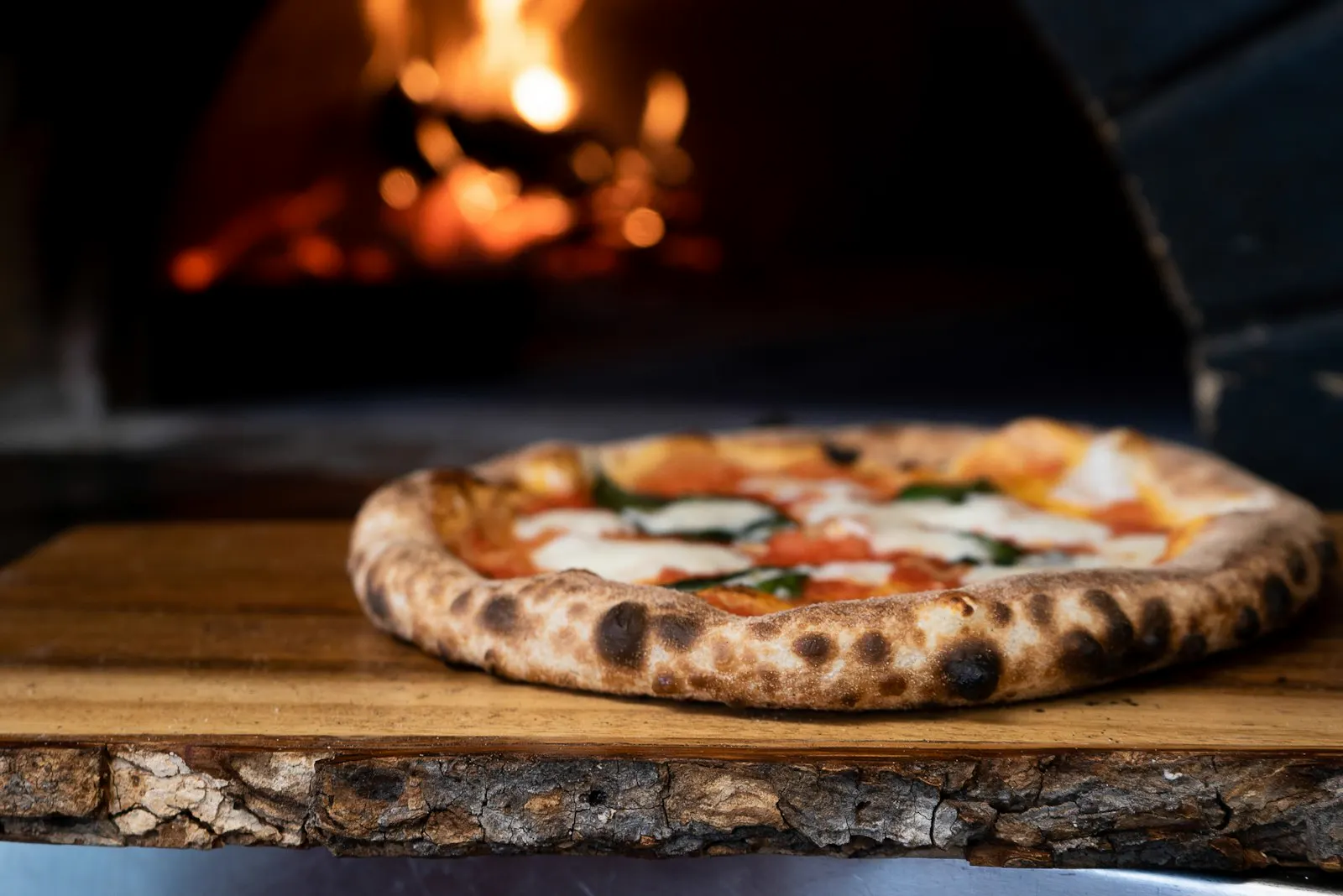 Wood-fired pizza in front of a brick oven